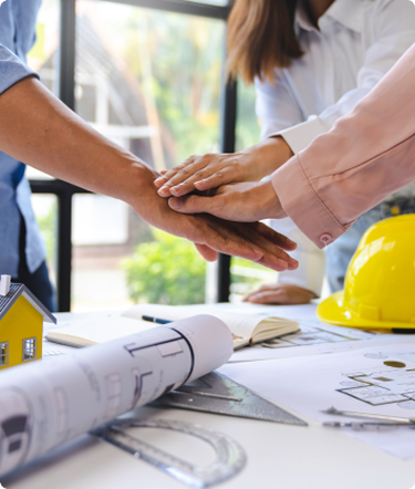 Equipo de arquitectos uniendo las manos sobre planos de obra